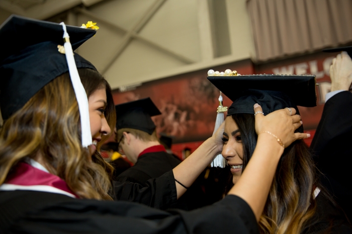 Female student in cap and gown smiling in line with other students.