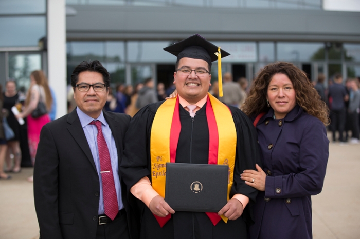 Female student in cap and gown smiling in line with other students.