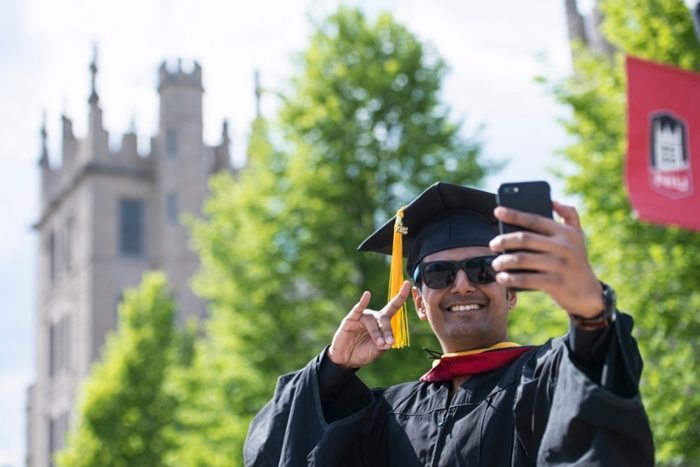 Male graduate student receiving his hood from faculty.